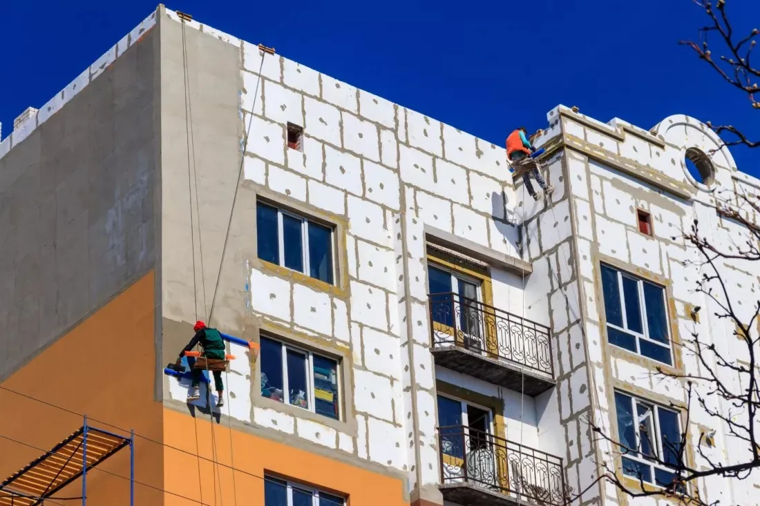 Des ouvriers isolent la facade d'un ancien immeuble d'habitation