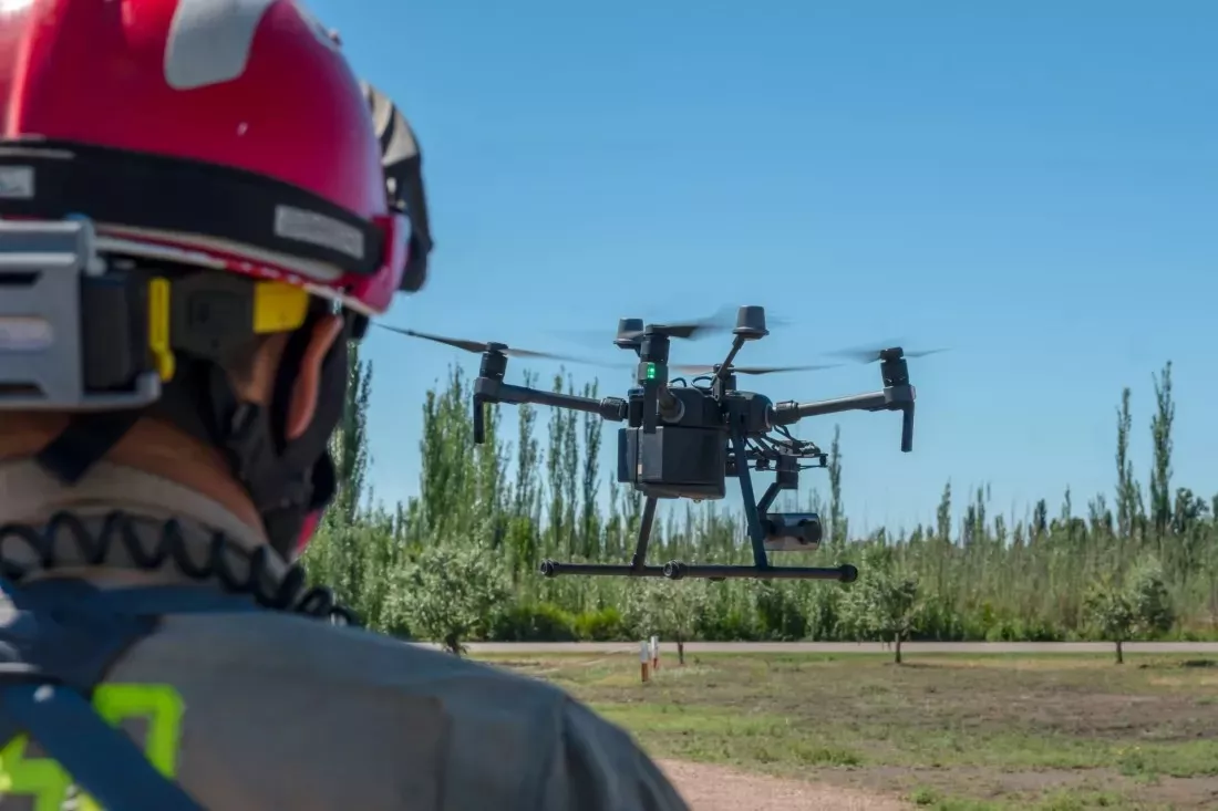 Pompier casque observant un drone qui survole un champ