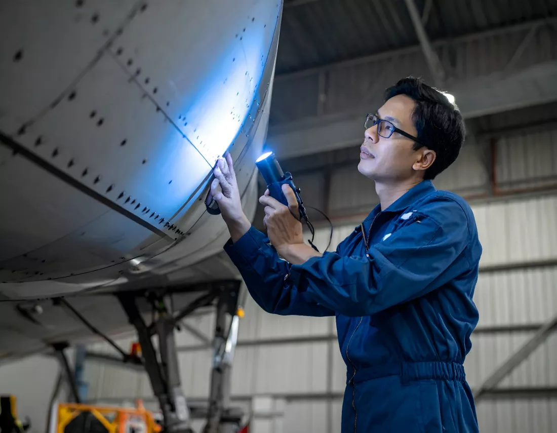 Un technicien inspecte un avion dans un hangar