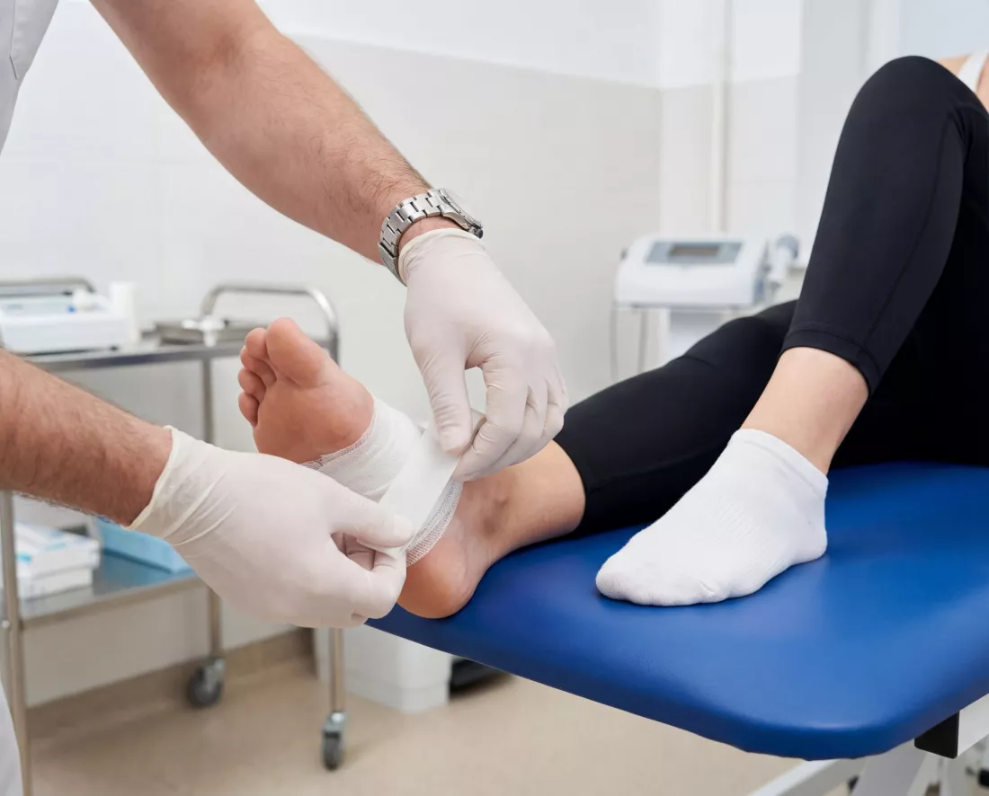 Medecin bandant le pied de la patiente en cabinet
