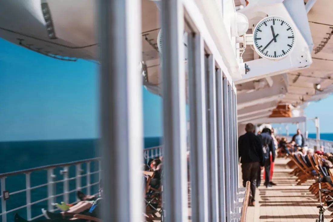 Des passagers marchent sur le pont ensoleille d'un navire de croisiere en mer